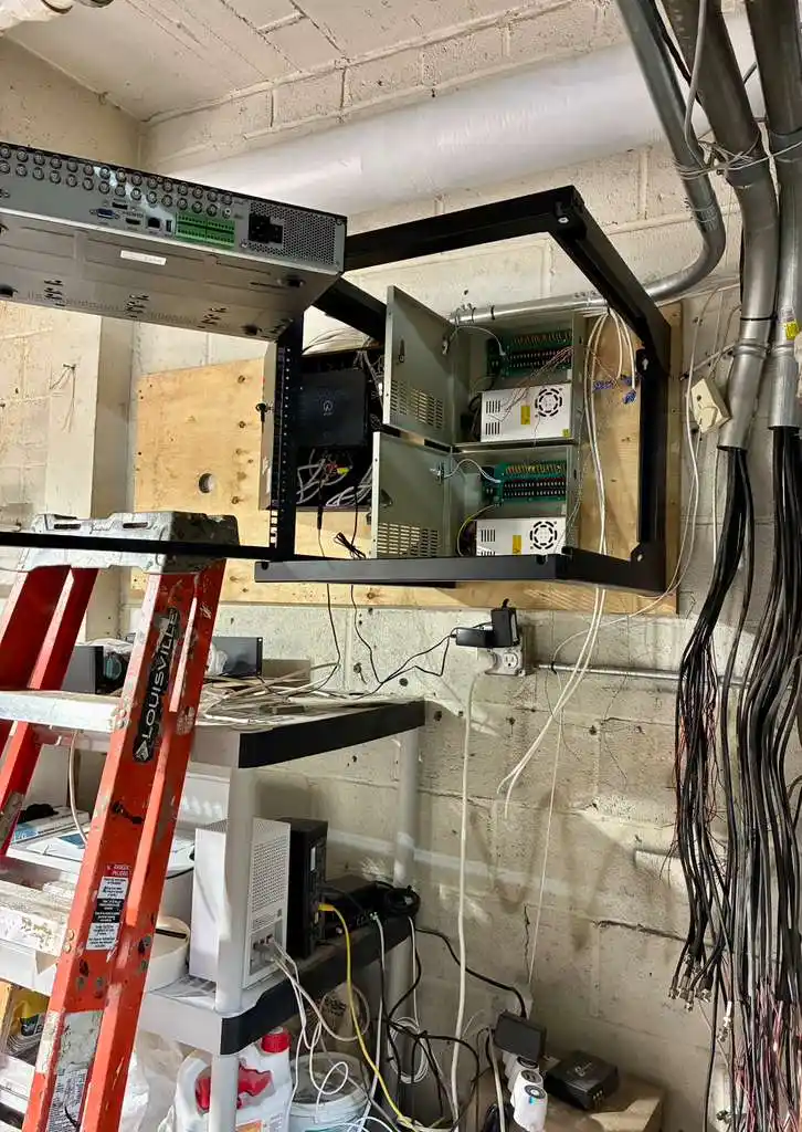 Security equipment rack with NVR and power supplies in a cinder block utility room