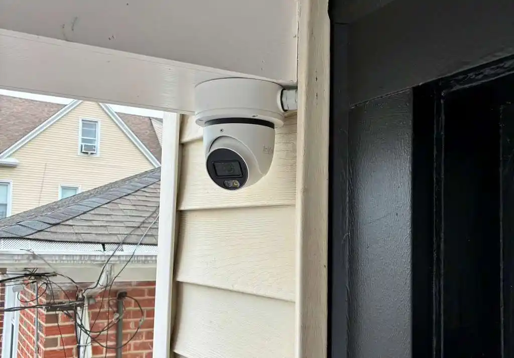 White turret security camera mounted under a residential porch eave