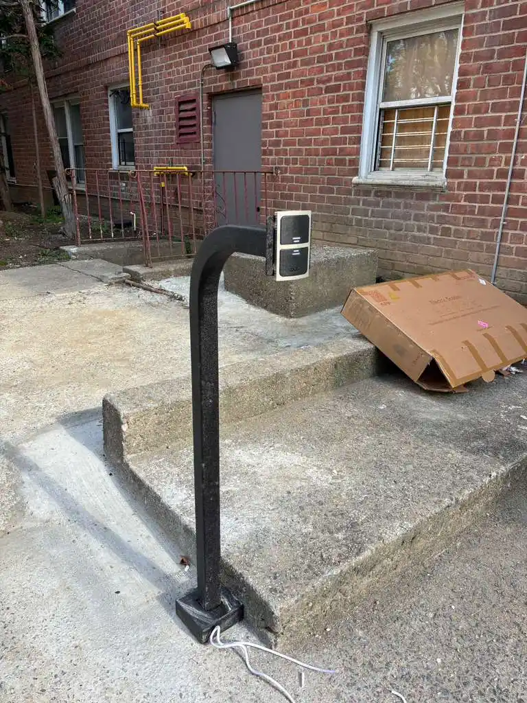 Freestanding access control card reader post at a brick building entry with steps