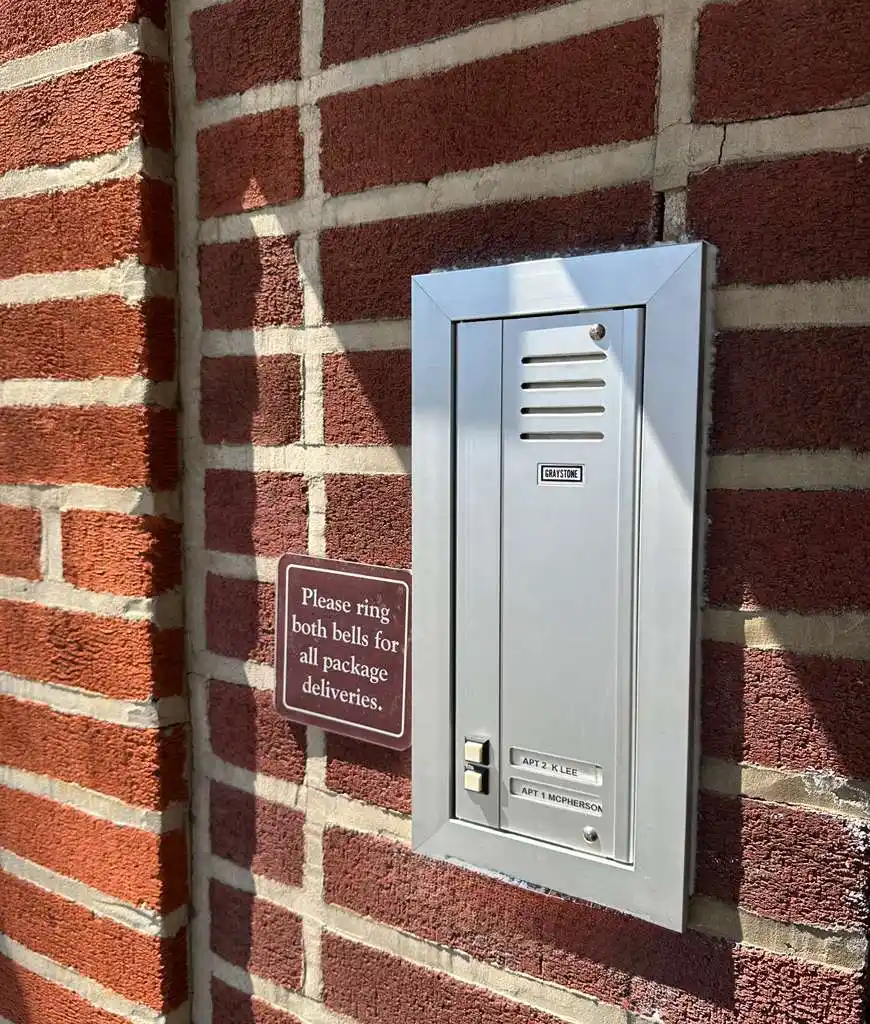 Graystone two-unit audio intercom panel flush-mounted in a brick building facade