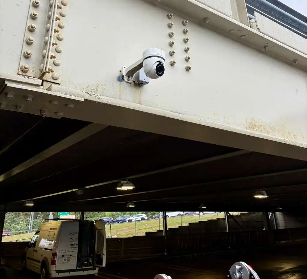 PTZ security camera mounted on a steel bridge beam with JAJO's van below