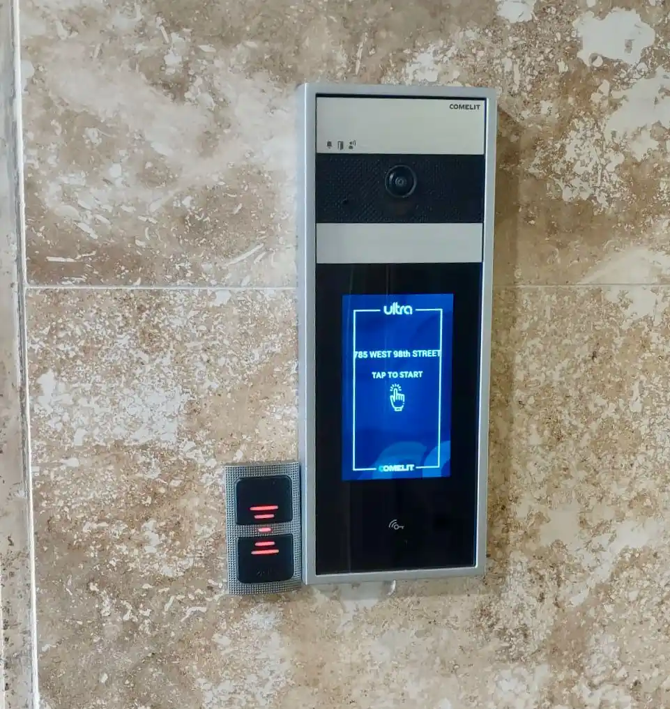 Comelit Ultra touchscreen video intercom and access reader on a marble lobby wall