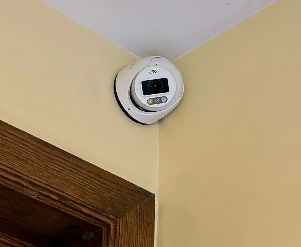 White dome security camera mounted in an interior corner above a door