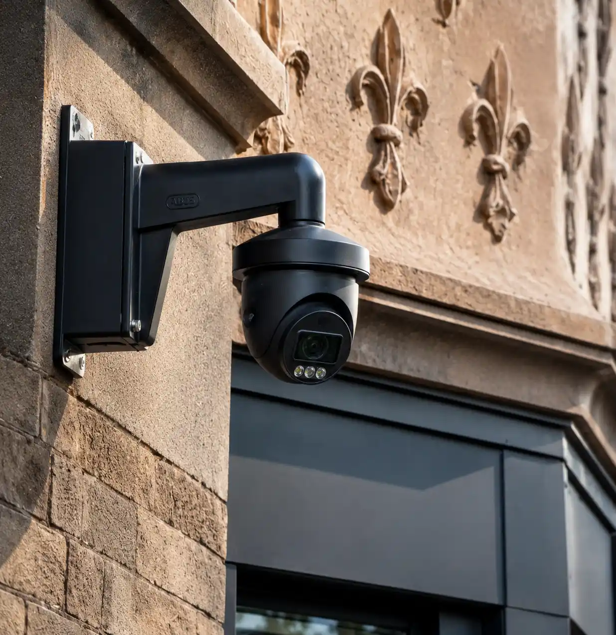 Black PTZ security camera mounted on a brownstone facade