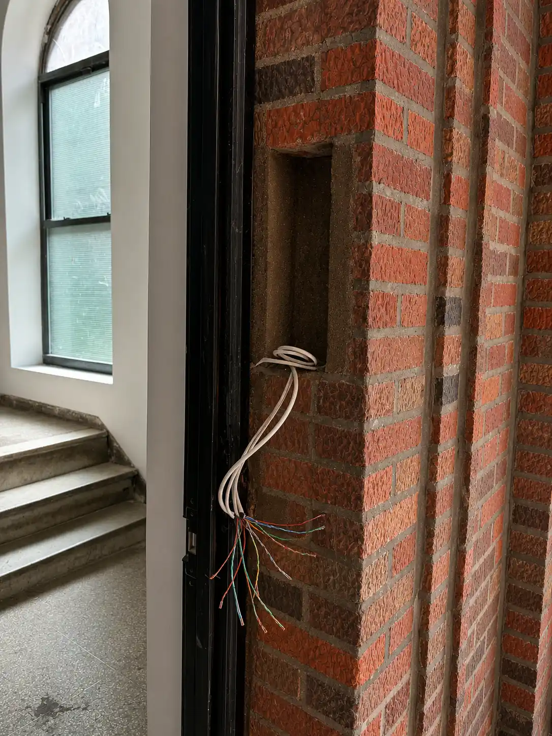 Low-voltage prewire emerging from a brick entry wall