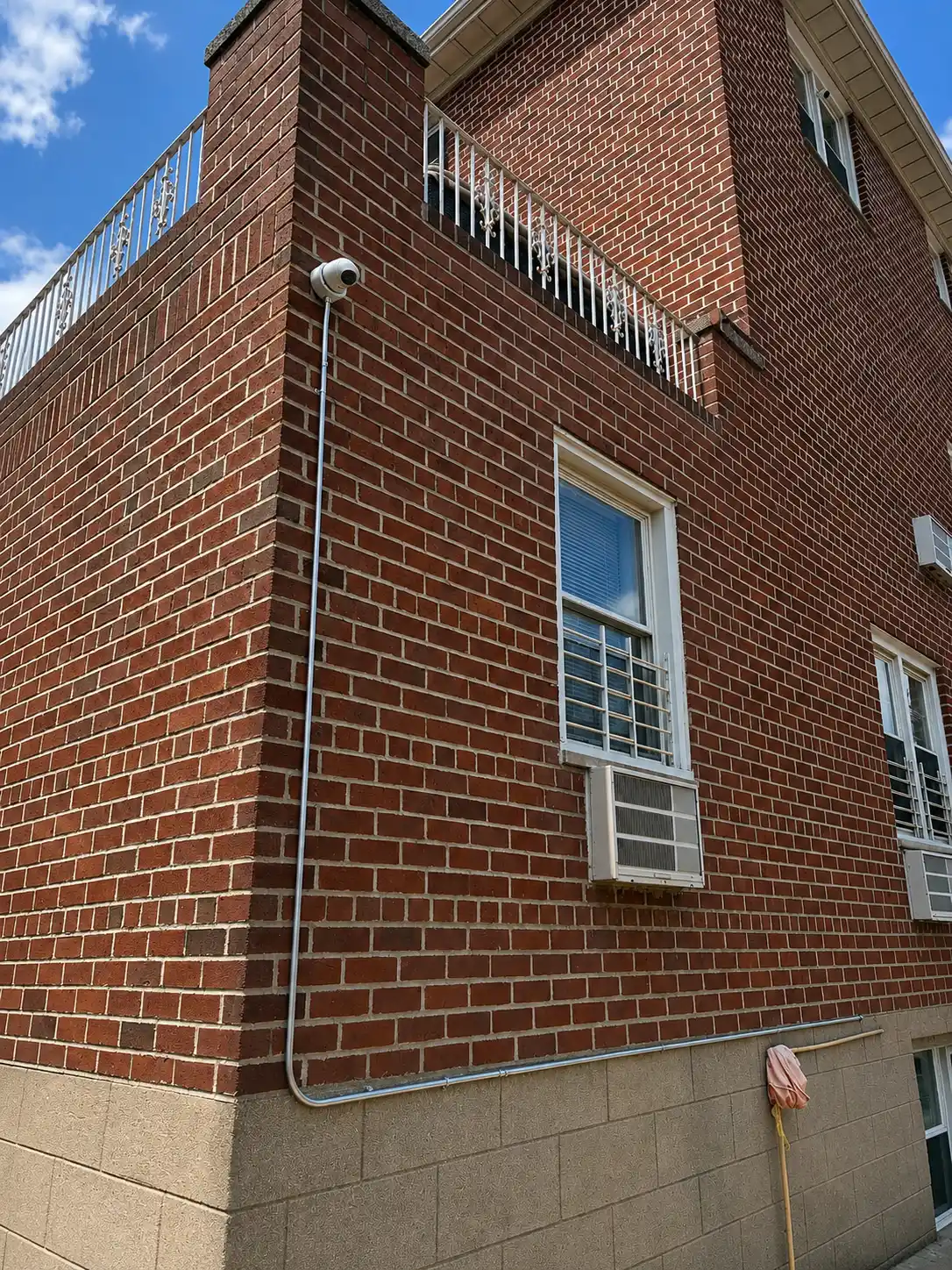 Residential brick building with exterior camera conduit and corner coverage