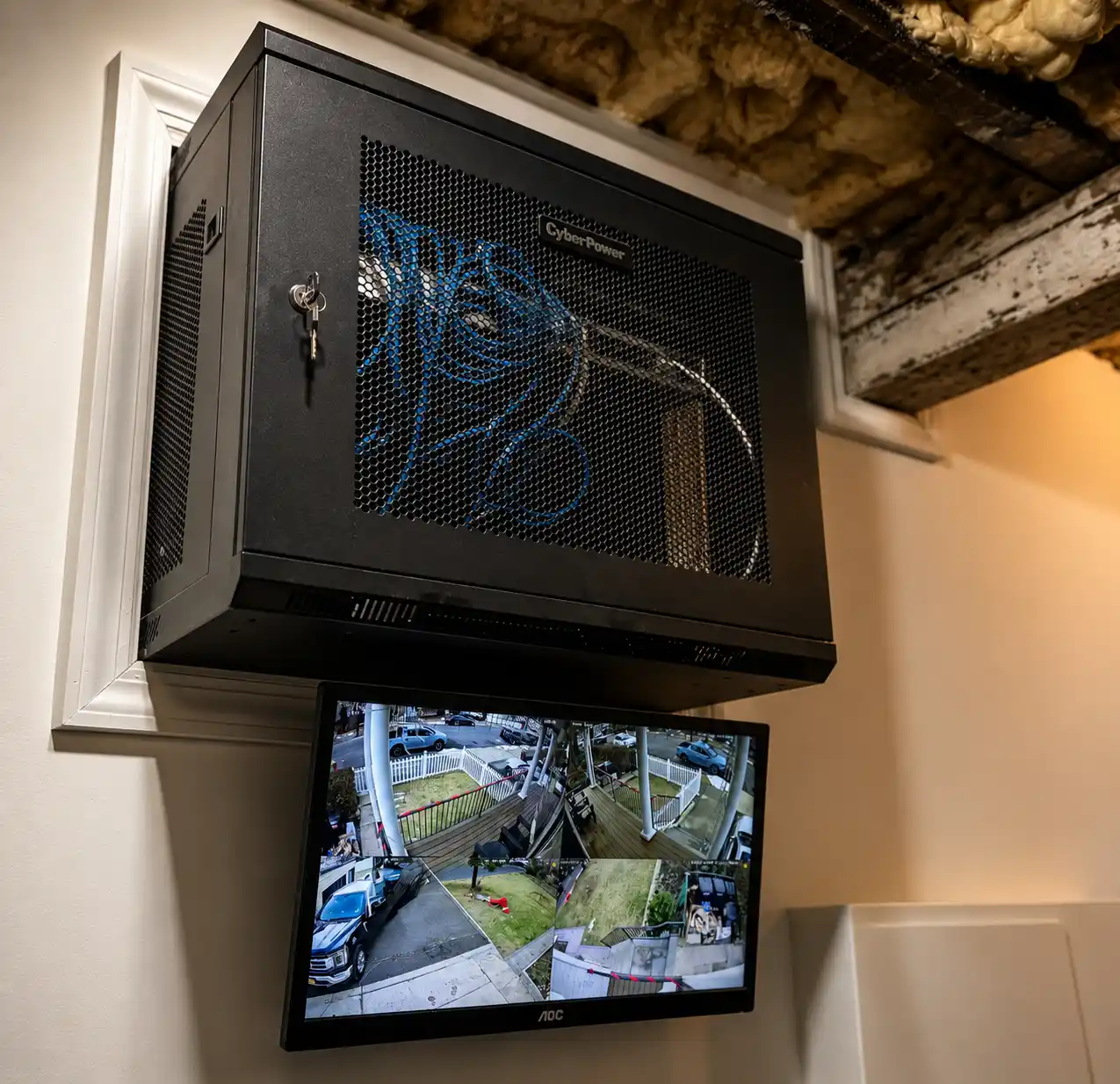 Wall-mounted security rack with monitor showing multiple camera views