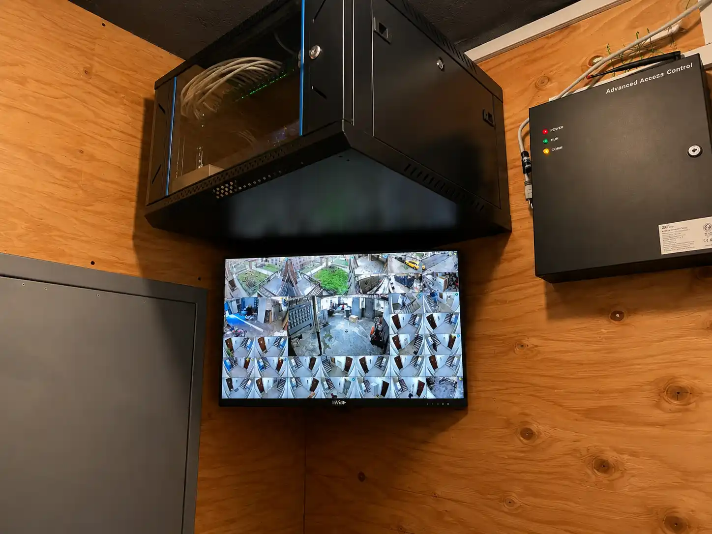 Security head-end monitor and equipment rack on a plywood wall